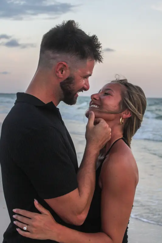 Couple smiling at each other by the ocean, photographed by Miranda Rae