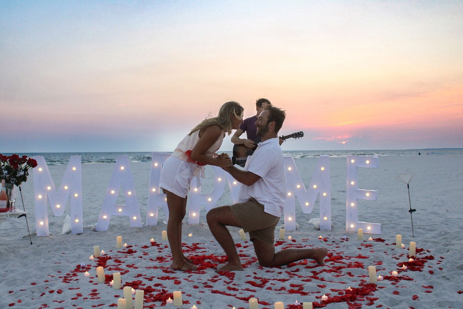 Beach proposal with Marry Me lights at sunset, photographed by Miranda Rae