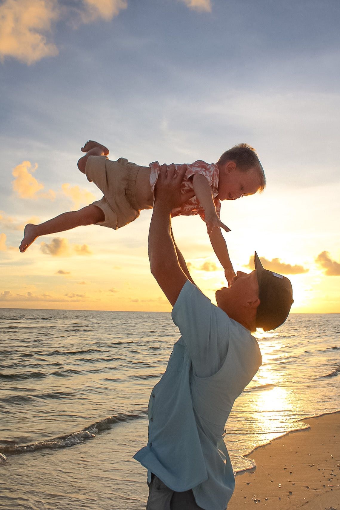 Dad lifting his little one into the air at sunset on a Florida beach