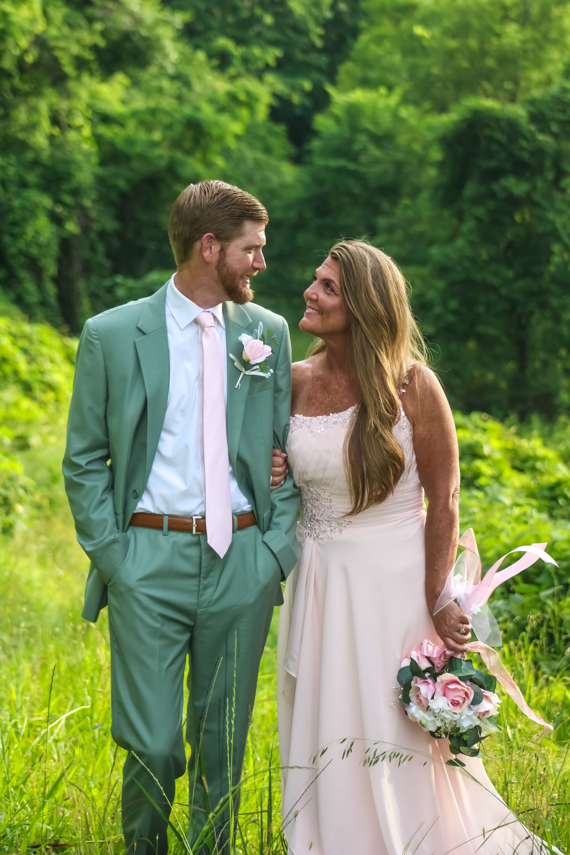 Bride and groom on their wedding day, groom in a sage green suit, photographed by Miranda Rae